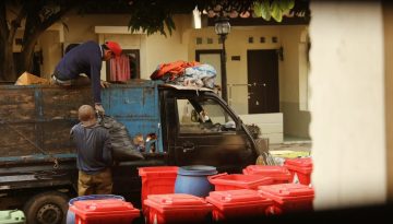 dump truck beside red garbage bins